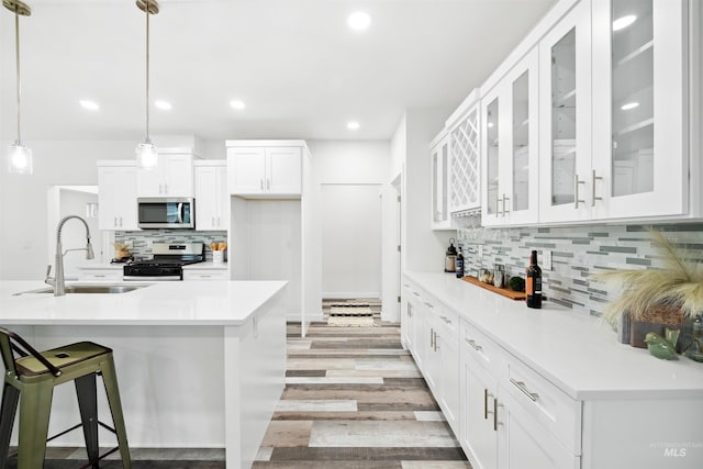 kitchen with light countertops, stainless steel appliances, light wood-style floors, white cabinetry, and a sink