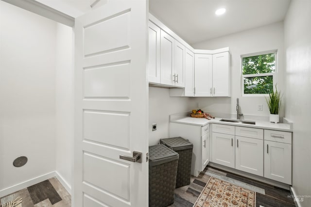 washroom featuring wood finished floors, cabinet space, hookup for an electric dryer, and a sink