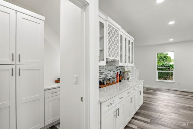 kitchen featuring glass insert cabinets, wood finished floors, recessed lighting, light countertops, and decorative backsplash