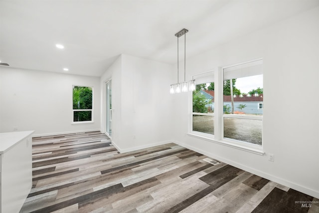 unfurnished dining area featuring recessed lighting, wood finished floors, and baseboards