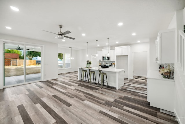 kitchen with backsplash, light countertops, appliances with stainless steel finishes, white cabinetry, and a ceiling fan