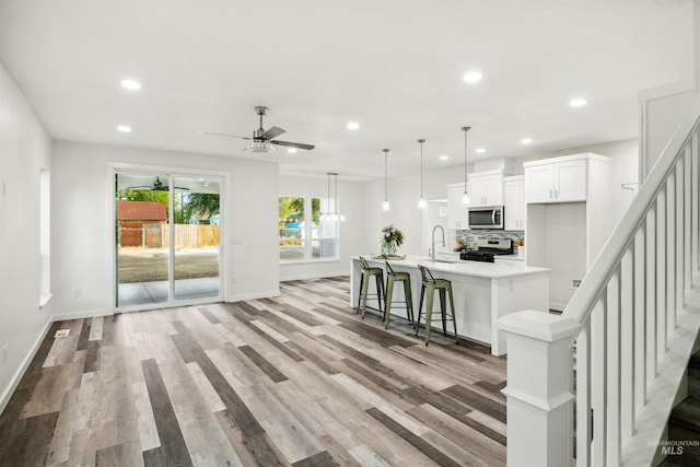 kitchen with backsplash, light wood-type flooring, light countertops, white cabinets, and stainless steel appliances