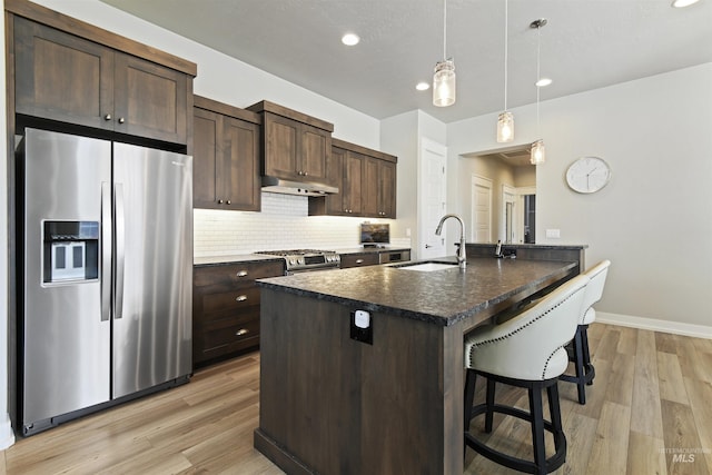 6164 N Winward Ln, Meridian, ID 83646 - kitchen with appliances with stainless steel finishes, a sink, dark brown cabinetry, a breakfast bar, and light wood-style floors