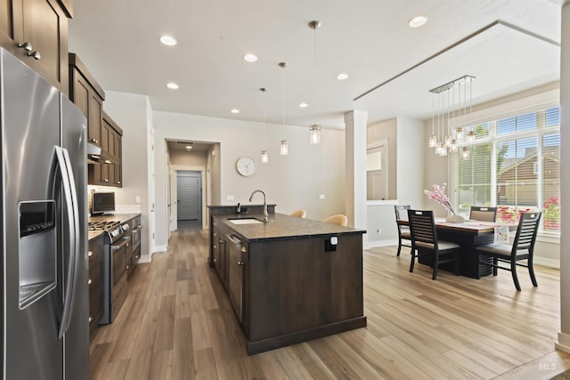 6164 N Winward Ln, Meridian, ID 83646 - kitchen with appliances with stainless steel finishes, a sink, dark brown cabinetry, baseboards, and light wood-style flooring