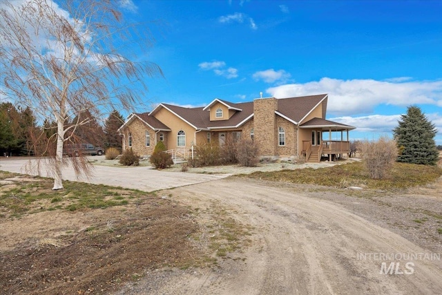 view of front of property with covered porch, driveway, and a chimney