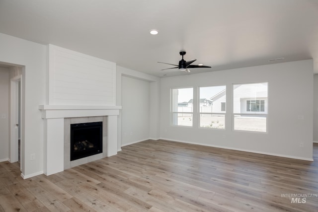 unfurnished living room with a fireplace, light wood-type flooring, and ceiling fan