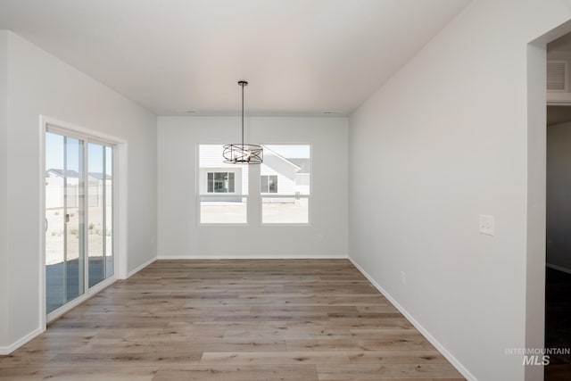 unfurnished dining area featuring a notable chandelier and light wood-type flooring