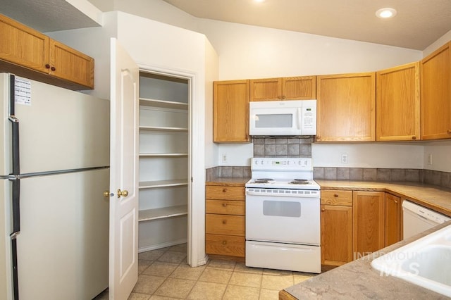 kitchen with white appliances, light tile patterned flooring, recessed lighting, light countertops, and vaulted ceiling