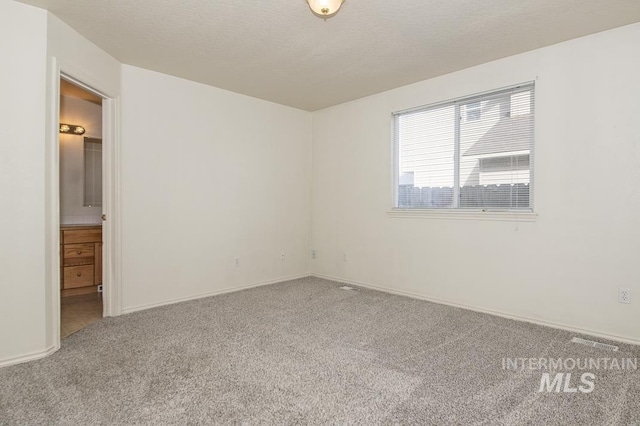 carpeted empty room with visible vents, baseboards, and a textured ceiling