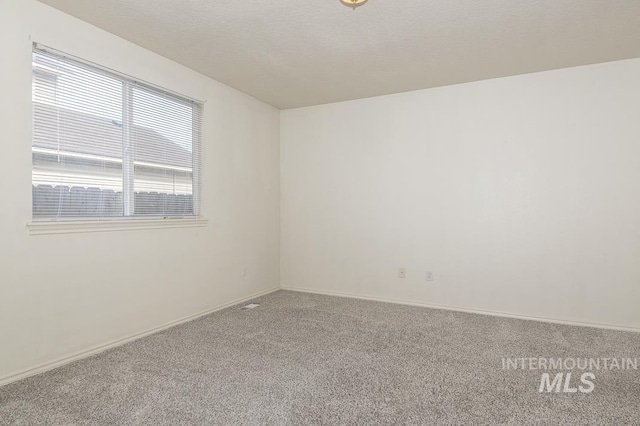 unfurnished room featuring a textured ceiling, baseboards, and carpet