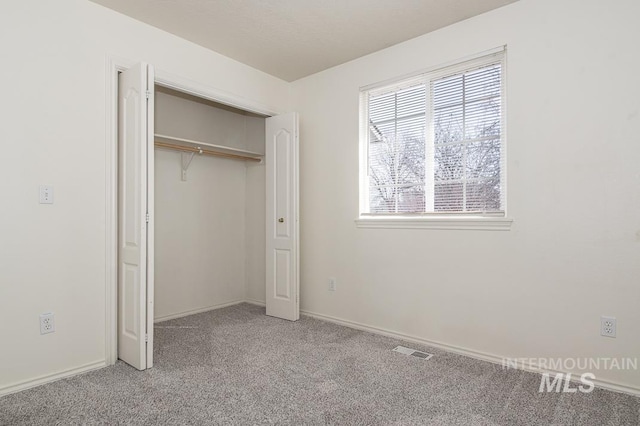 unfurnished bedroom with a closet, visible vents, multiple windows, and carpet