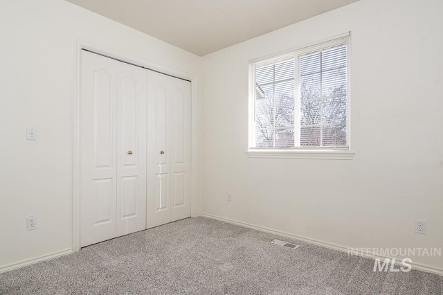 unfurnished bedroom with a closet, visible vents, baseboards, and carpet