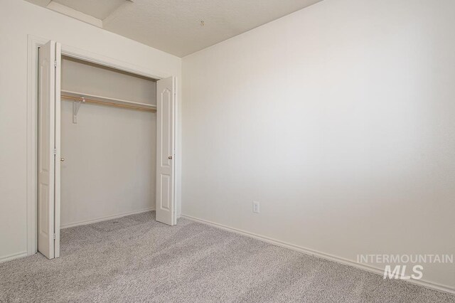 unfurnished bedroom featuring a closet, baseboards, and carpet