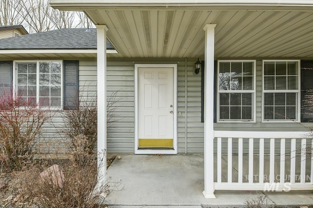 property entrance with covered porch and a shingled roof