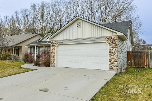 view of front of home featuring driveway, stone siding, fence, a front yard, and an attached garage