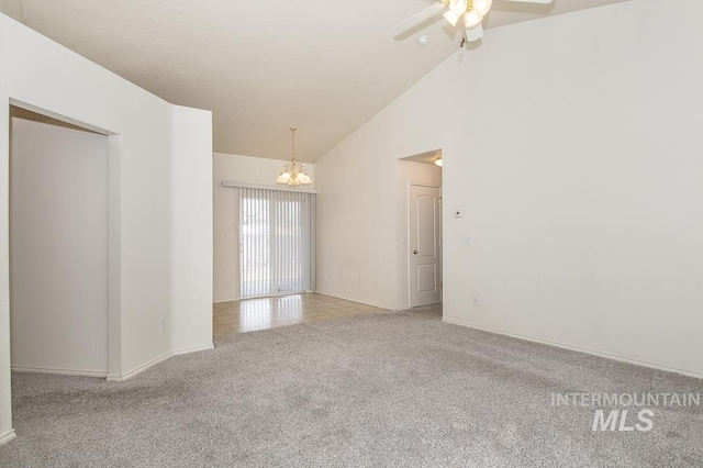 spare room with high vaulted ceiling, ceiling fan with notable chandelier, and light carpet