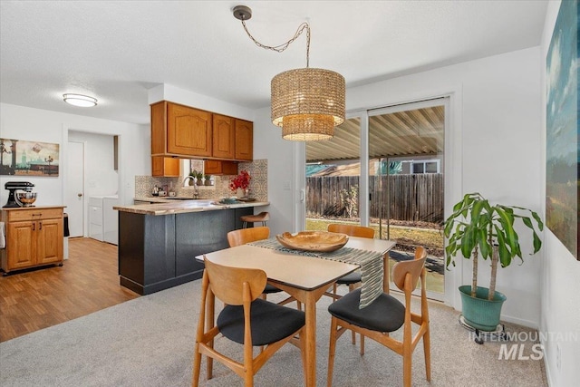 dining space featuring light carpet, an inviting chandelier, light wood-type flooring, and a textured ceiling