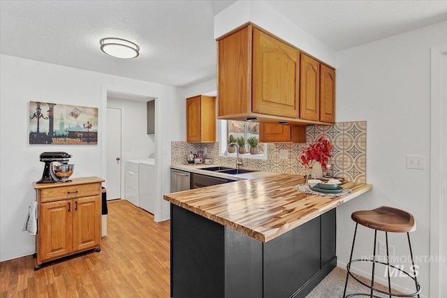 kitchen with decorative backsplash, butcher block countertops, a peninsula, washer and dryer, and a sink