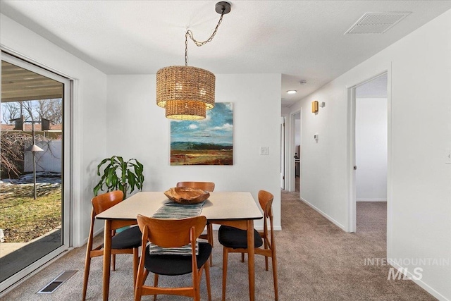 carpeted dining room with visible vents, a textured ceiling, and baseboards