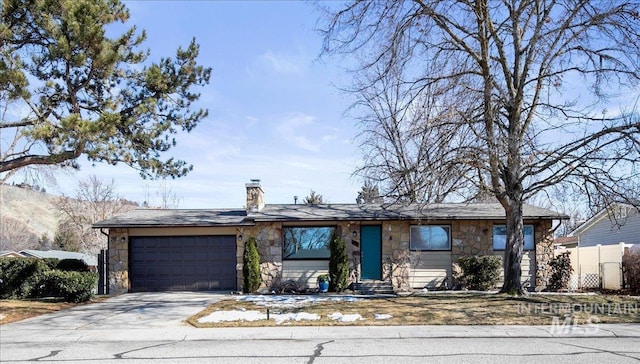 ranch-style home with a chimney, fence, a garage, stone siding, and driveway