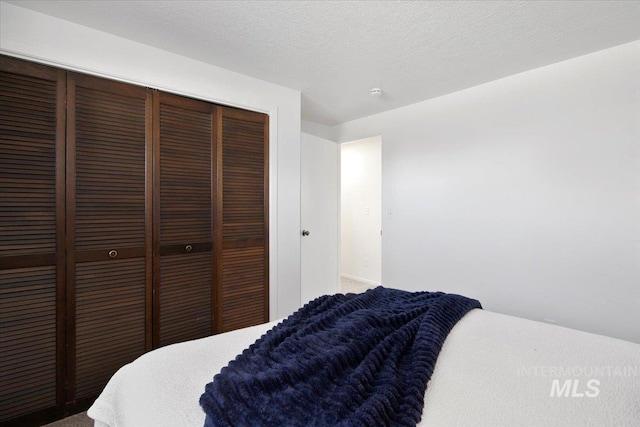 carpeted bedroom featuring a closet and a textured ceiling