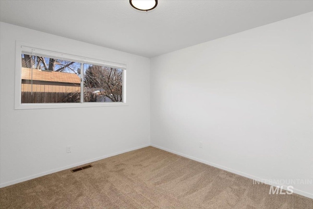 carpeted spare room featuring baseboards and visible vents