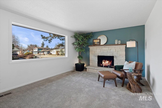 sitting room featuring a textured ceiling, a fireplace, carpet flooring, visible vents, and baseboards