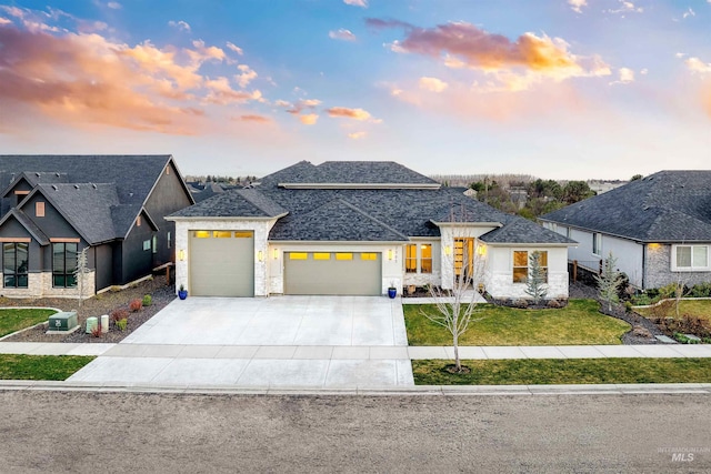 view of front of house with driveway, a front yard, stone siding, cooling unit, and a garage
