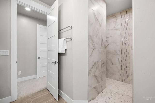 bathroom with baseboards and tiled shower