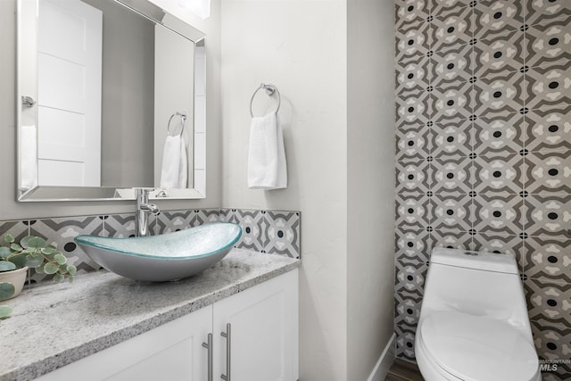 bathroom with toilet, decorative backsplash, and vanity