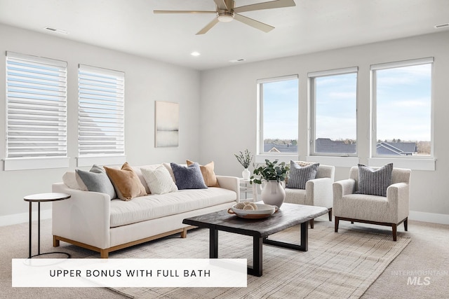 living room featuring baseboards, ceiling fan, light carpet, and a wealth of natural light