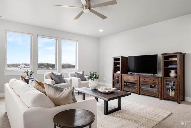 living room with a ceiling fan, light carpet, baseboards, and a healthy amount of sunlight