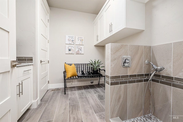 interior space featuring baseboards, wood finish floors, and tiled shower