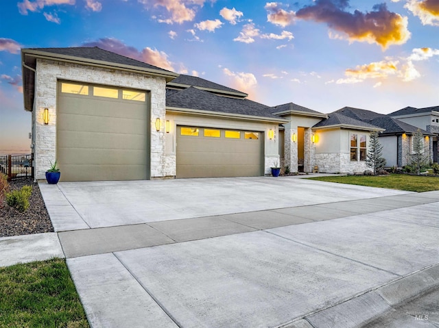 prairie-style house featuring stone siding, concrete driveway, and an attached garage