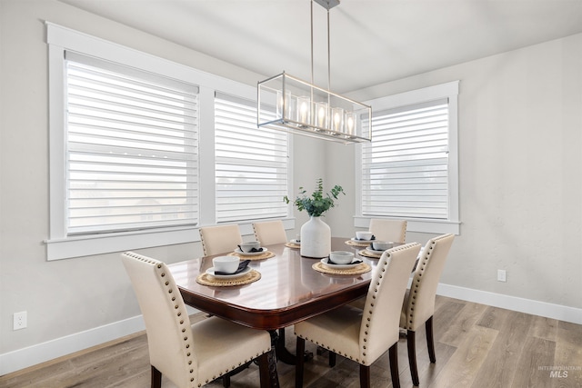 dining room with baseboards, light wood-type flooring, a chandelier, and a healthy amount of sunlight