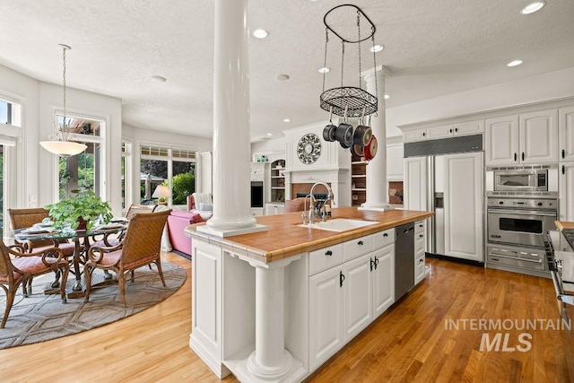 4119 N Park Ln, Eagle, ID 83616 - kitchen with ornate columns, built in appliances, a textured ceiling, open floor plan, and an island with sink