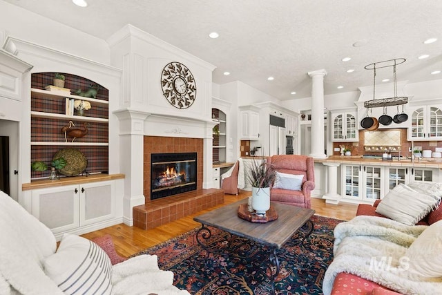 4119 N Park Ln, Eagle, ID 83616 - living area featuring recessed lighting, decorative columns, light wood-style floors, a tiled fireplace, and a textured ceiling
