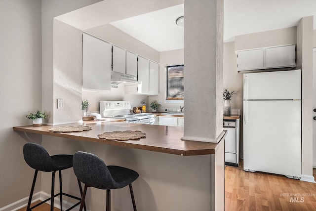 kitchen with white cabinetry, a kitchen breakfast bar, kitchen peninsula, light hardwood / wood-style floors, and white appliances