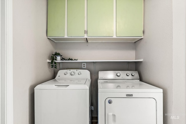 clothes washing area featuring cabinets and washing machine and clothes dryer