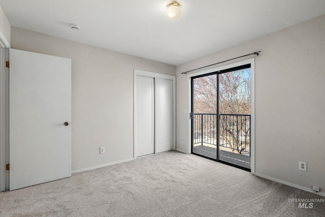 unfurnished bedroom featuring access to outside, a closet, and light colored carpet