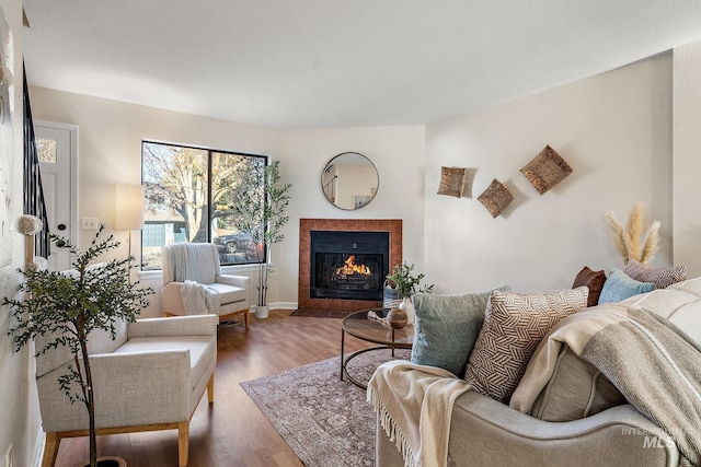 living room with wood-type flooring and a tiled fireplace