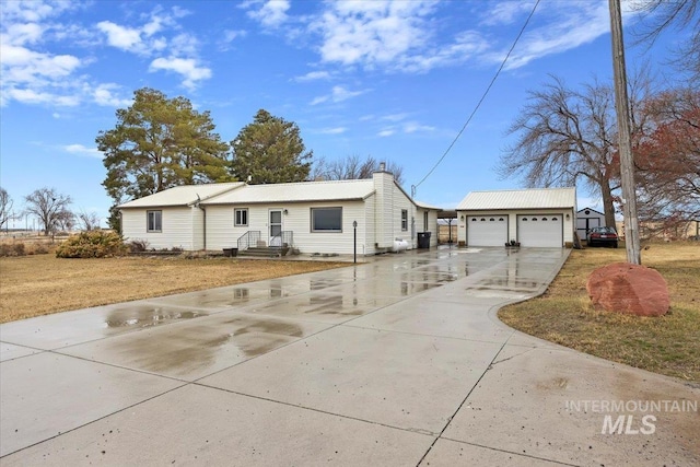 view of front of home with a chimney, a garage, concrete driveway, and an outdoor structure