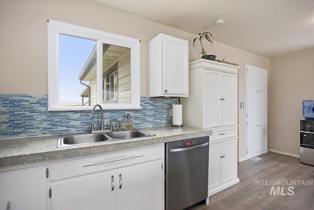 kitchen featuring a sink, white cabinets, light countertops, and stainless steel dishwasher