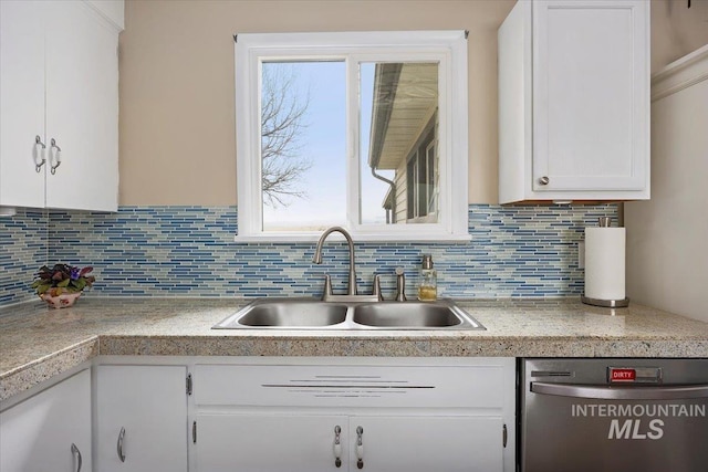 kitchen with dishwasher, light countertops, decorative backsplash, white cabinets, and a sink