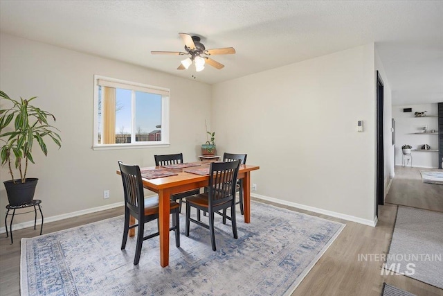 dining area with a textured ceiling, baseboards, ceiling fan, and wood finished floors