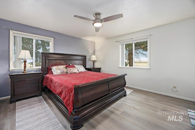 bedroom featuring baseboards, a textured ceiling, wood finished floors, and a ceiling fan