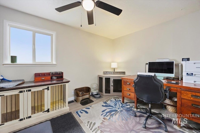 office space with baseboards and ceiling fan