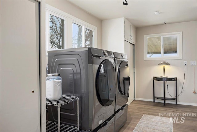 laundry area featuring cabinet space, washer and dryer, light wood-type flooring, and baseboards
