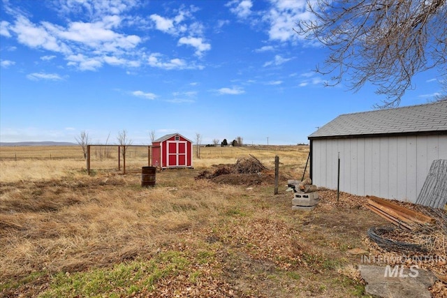 view of yard with a storage shed, an outdoor structure, and a rural view