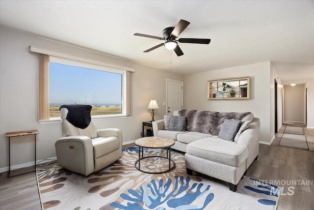 living area featuring wood finished floors, baseboards, and ceiling fan
